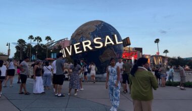 Excited guests surround the iconic Universal globe at the entrance to Universal Studios on a sunny day, ready for an action-packed adventure.