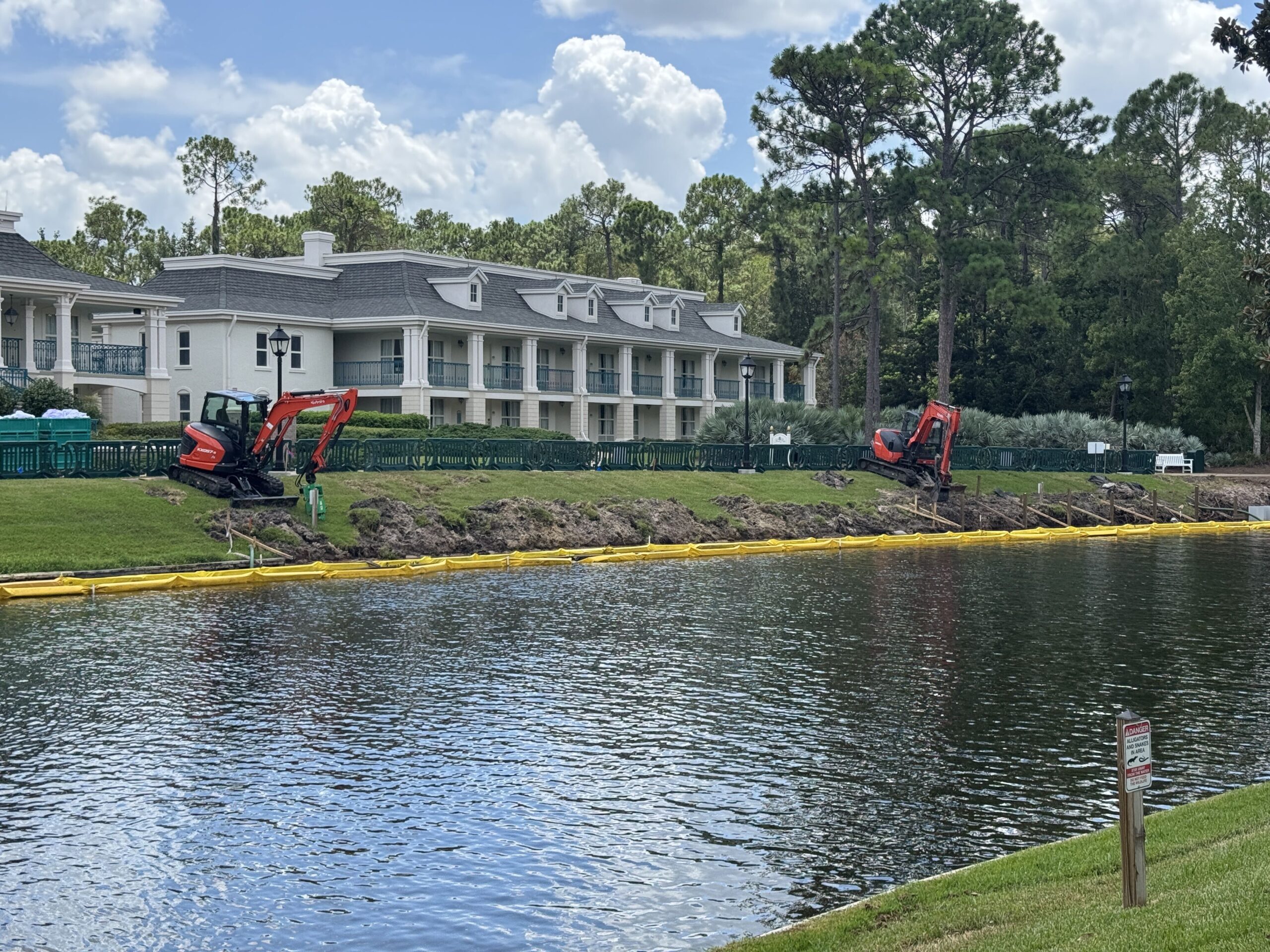 Two construction vehicles further along the river are being used to excavate the land and remove the old wall.