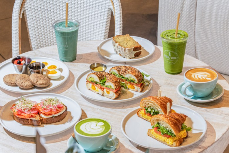 A spread of various salads, wraps and drinks. 