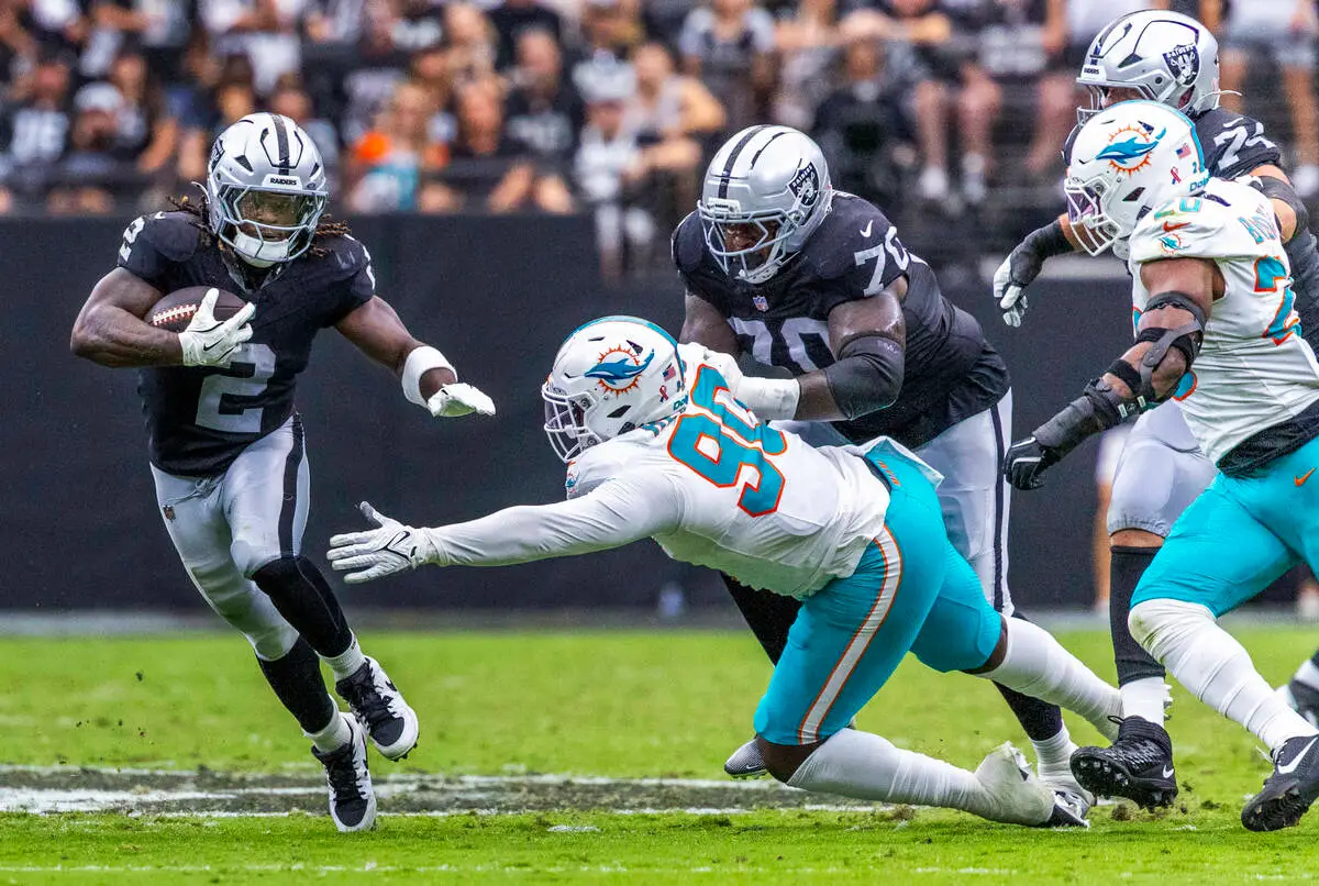 Raiders running back Ashton Jeanty (2) evades a tackle attempt by Miami Dolphins defensive end ...