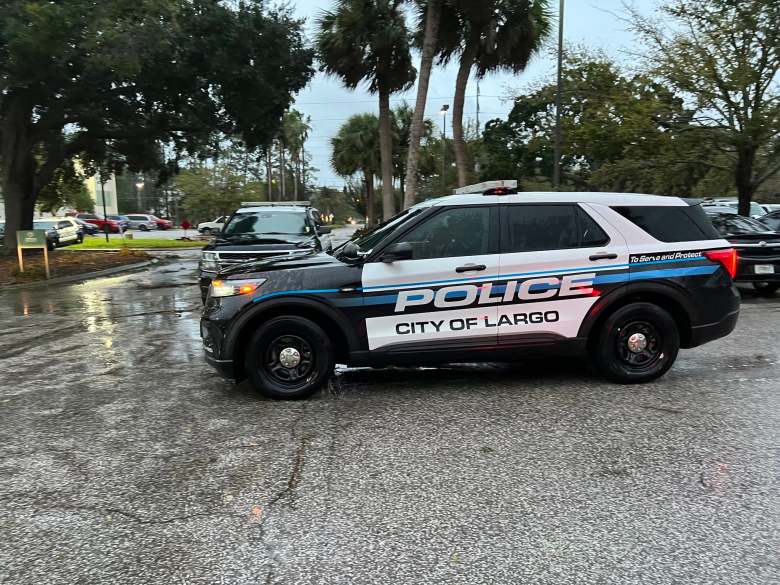 Side view of a City of Largo police cruiser, a black and white Ford Police Interceptor Utility,. parked on wet asphalt