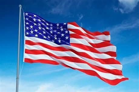 An American flag waving in the wind with a clear blue sky surrounding it.