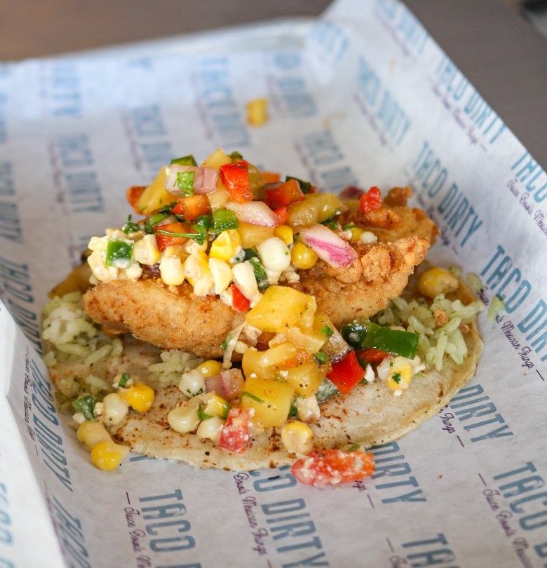 Alt-text options based on detail level: Concise: A crispy fried fish fillet topped with fresh corn, tomato, and red onion salsa.