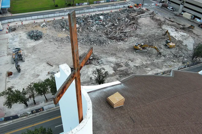 A cross from First Baptist Church of Jacksonville looms over the demolition site as construction workers use excavators to remove debris from the teardown of the former main auditorium of downtown church. The building was sold to developer Gateway Jax , which plans to build an apartment tower and a Publix store at the site. | See more demolition photos