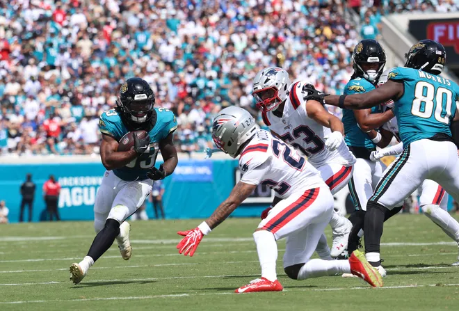 Sep 27, 2026; Jacksonville, Florida, USA; Jacksonville Jaguars running back Bhayshul Tuten (33) runs for a gain past New England Patriots cornerback Charles Woods (22) during the second quarter at EverBank Stadium. Mandatory Credit: Morgan Tencza-Imagn Images
