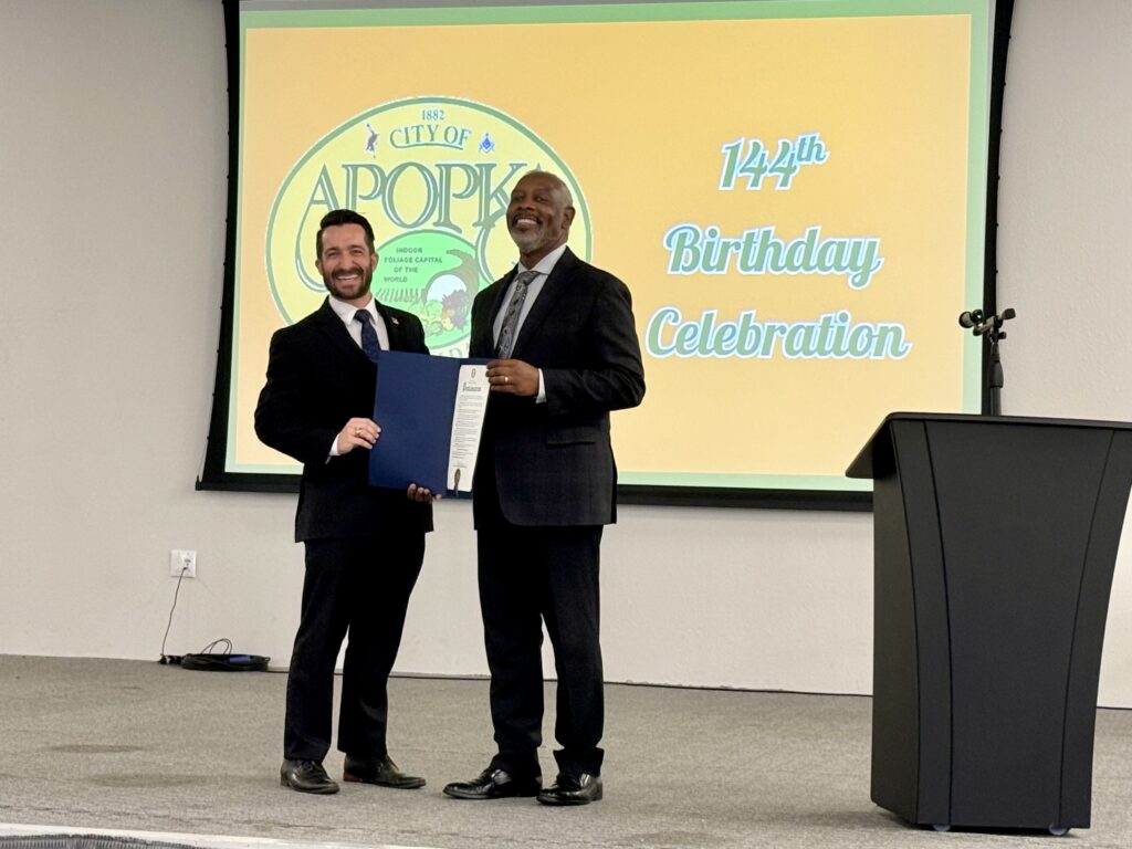 Apopka Mayor Nick Nesta (left) and Orange County Mayor Jerry Demings (right) pose with the 144th anniversary proclamation.