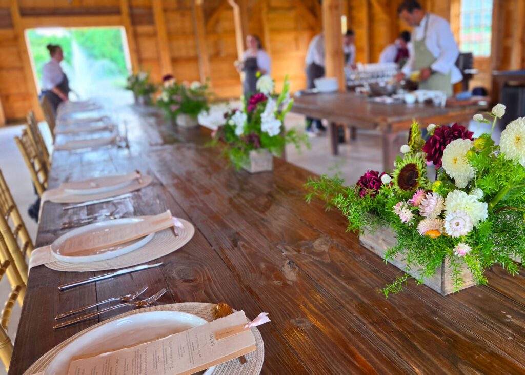 A long dinner table set with plates and flowers.