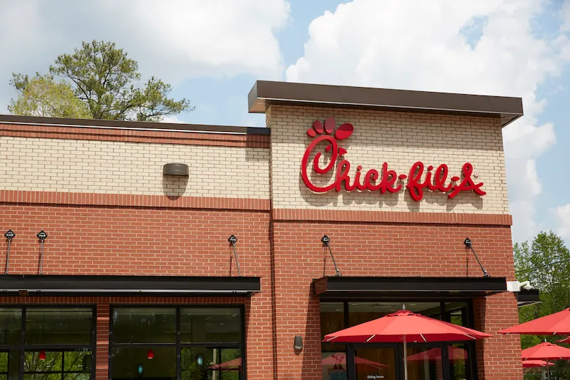 Exterior of a Chick-fil-A restaurant with the red Chick-fil-A sign above an outdoor patio