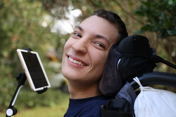 JJ Holmes, 17, outside his family's Longwood home in a 2021 file photo. JJ has cerebral palsy and uses a wheelchair and an iPad that he types with his nose to communicate. (Ricardo Ramirez Buxeda/ Orlando Sentinel)