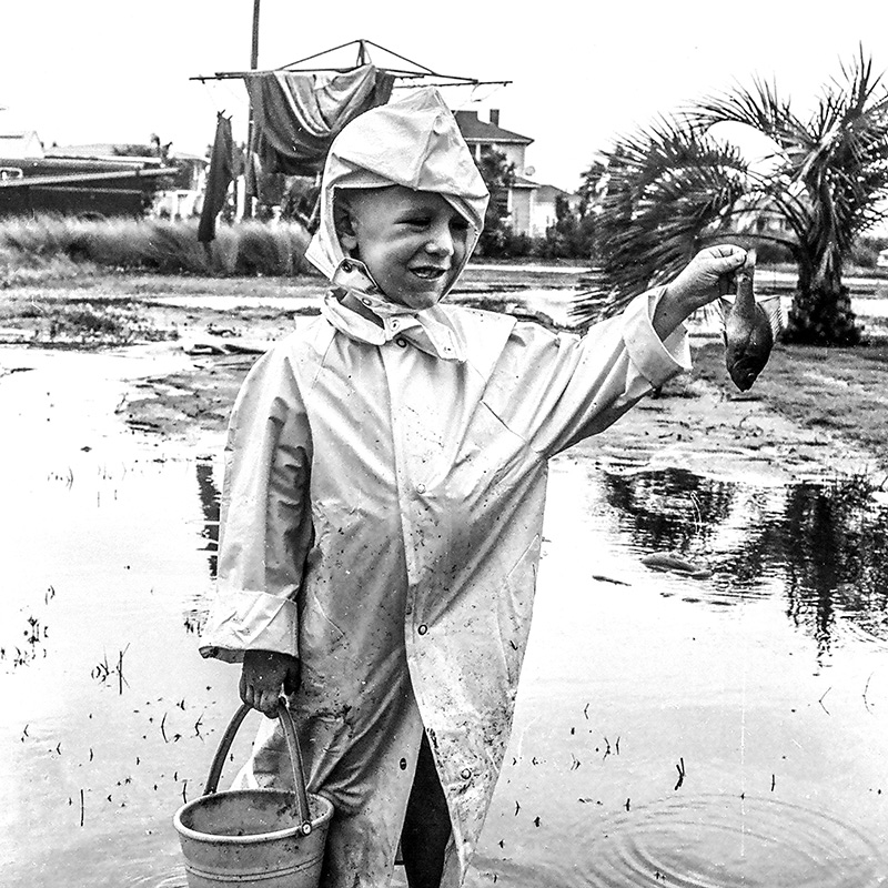 Young boy holds up a fish in his backyard, while JEA linemen work on power interruptions after Hurricane Dora