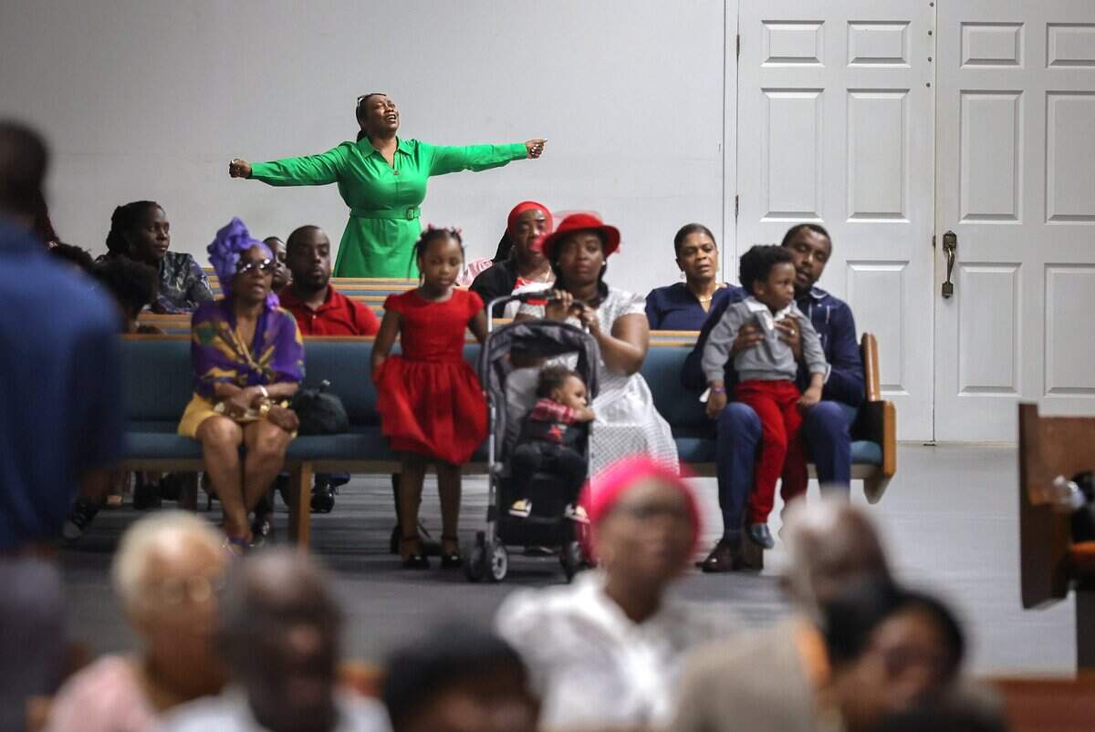 A congregant stands in prayer at the back of Bethel Evangelical Baptist Church in Miami Gardens, Fla., on Sunday, Sept. 13, 2026, as the congregation copes with the heavy burden left by the end of Temporary Protected Status, which has forced tens of thousands of Haitians in South Florida into immigration limbo. Many now fear for their safety and have chosen to stay home on Sundays-a decision made with great difficulty.