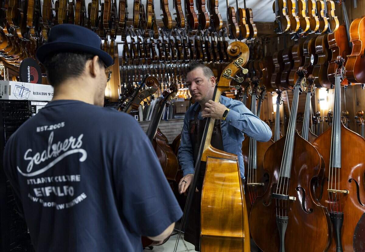 Miami String Haus founder Charles Winters, right, talks with a musician visiting his store on Thursday, Aug. 6, 2026, in El Portal, Fla. Miami String Haus is a home-based luthier shop where customers can buy, repair and maintain string instruments, including violins, violas, cellos and double basses.
