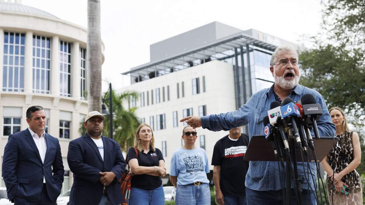 Former Congressman Joe Garcia points back to Doral City Hall during a gathering outside on Tuesday, Sept. 22, 2026, in Doral, Fla. Speakers asked Doral City Council to rescind the city's 287(g) agreement with U.S. Immigration and Customs Enforcement (ICE).