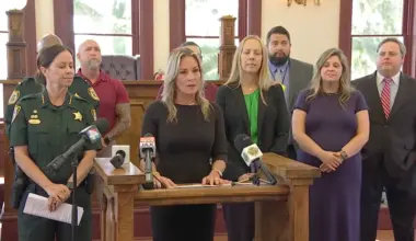 Clay County official stand in a line at a news conference, announcing a task force to target exploitive guardians.