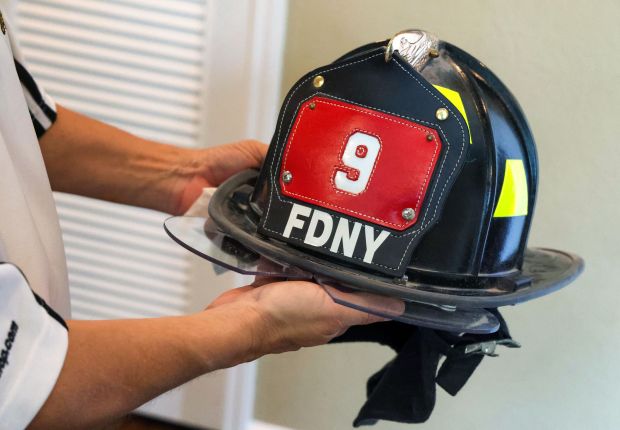 Neil Peraza holds a FDNY helmet given to him by a firefighter friend of his brother Rob Peraza, at Neil's home in Orlando, Wednesday, Sept. 2, 2027. Rob was on the 104th floor of the World Trade Center's north tower on Sept. 11, 2001, and was among the nearly 3,000 that were killed in the terrorist attack in New York City 25 years ago. (Joe Burbank/Orlando Sentinel)