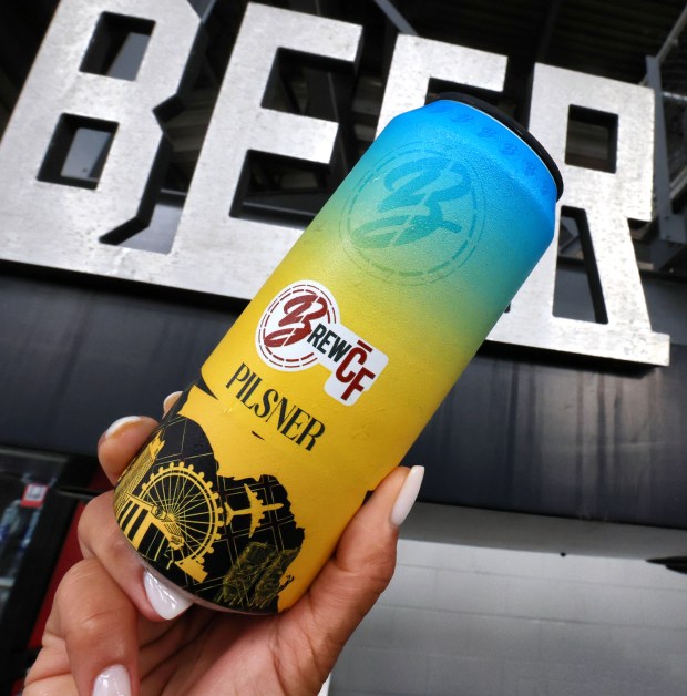 Shara Pathak, founder and CEO of Brewlando, holds up a can of pilsner one of their University of Central Florida-themed beers at the Acrisure Bounce House on campus, Aug. 21, 2026. The brewery is debuting its line of "BREW-CF" beers at the stadium in time for UCF's home opener Sept. 7. (Joe Burbank/Orlando Sentinel)
