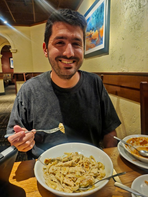 Olive Garden superfan Christian Simmons, 29, tucks into his favorite dish: fettuccine Alfredo with chicken. (Amy Drew Thompson/Orlando Sentinel)