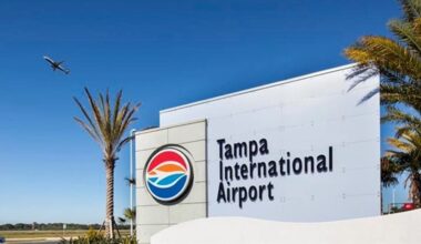 Sign for Tampa International Airport with airplane overhead and palm trees