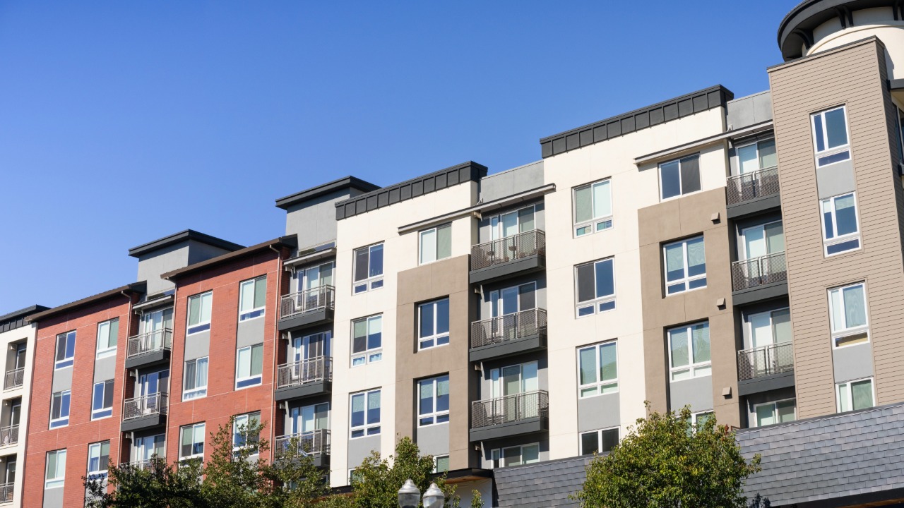 Exterior of a multistory apartment building with balconies and mixed exterior finishes.