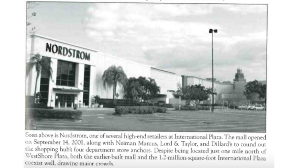 Black-and-white archival photo of the Nordstrom exterior at International Plaza in Tampa, with palm trees and an empty parking lot in front of the store.
