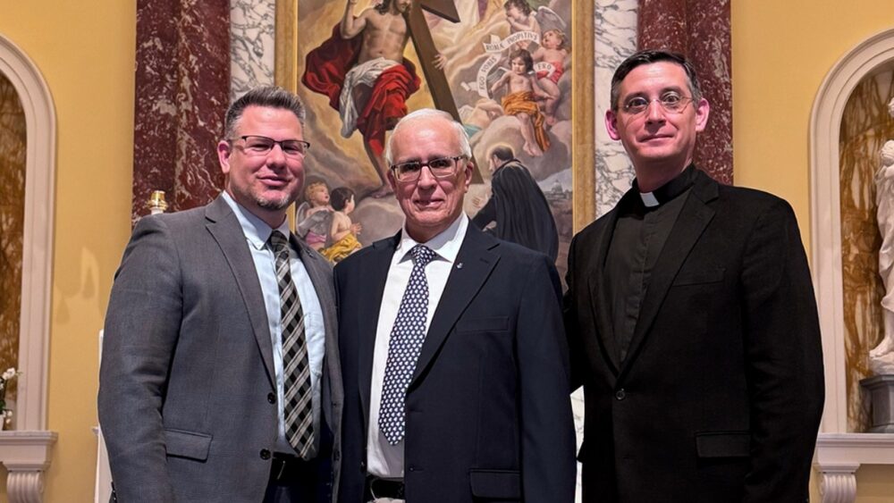 Nick Suszynski, Dr. Manuel Mon and Fr. Vincent Giacabazi stand together at Jesuit High School in Tampa.