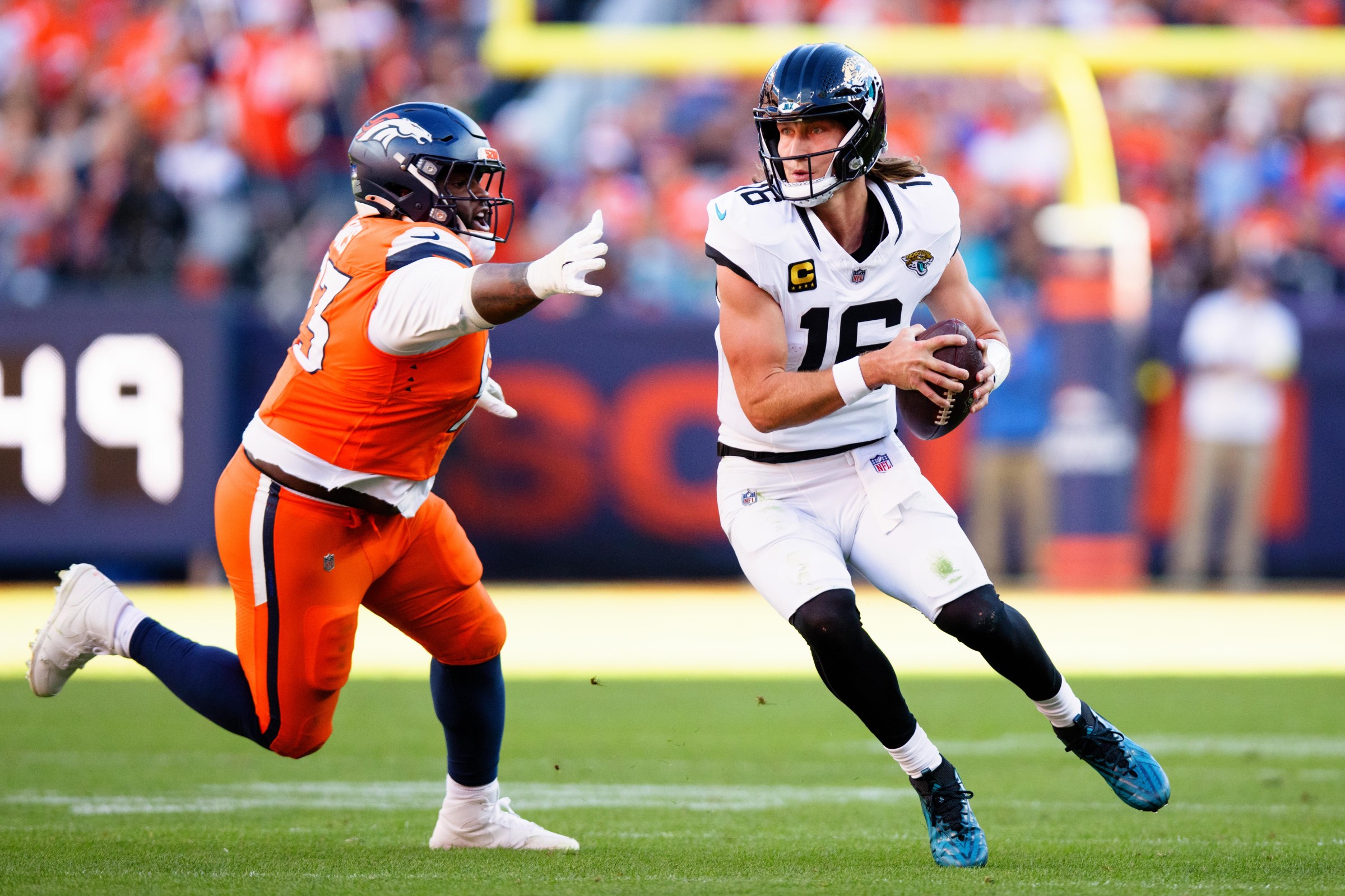 DENVER, CO - DECEMBER 21: Trevor Lawrence #16 of the Jacksonville Jaguars runs with the football past D.J. Jones #93 of the Denver Broncos during the first quarter at Empower Field at Mile High on December 21, 2025 in Denver, Colorado. (Photo by Justin Edmonds/Getty Images)