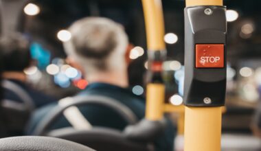 A bus stop button in a blurred interior bus setting with passengers in the background.