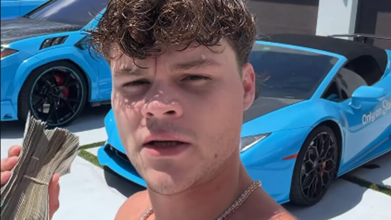 A selfie of Jack Doherty holding money with blue cars behind him.