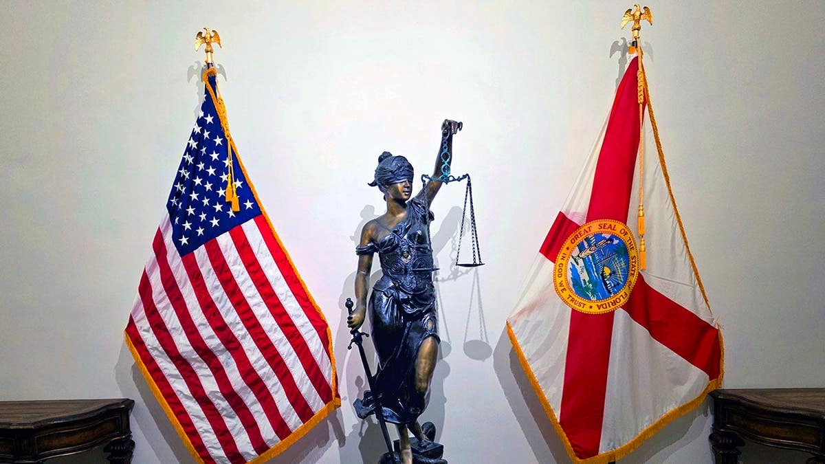 Lady Justice statue stands with American and Florida flags in the State Supreme Court building.