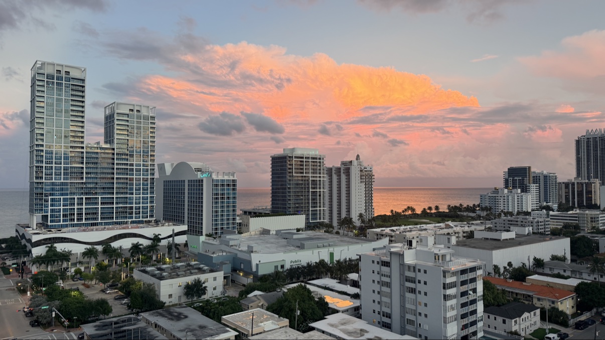 Miami Beach skyline at sunset with pink clouds over the ocean.