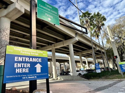 Tampa Convention Center parking garage sign that reads enter here with an arrow pointing under overpass.
