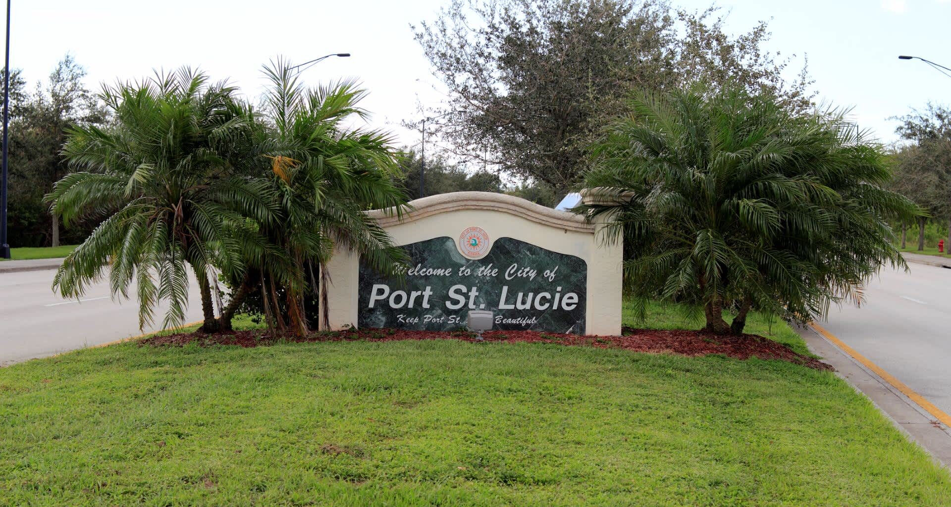 A welcome sign for the city of Port St. Lucie surrounded by palm trees and grass.
