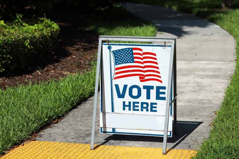 Vote Here sign on a sidewalk walkway leading to a polling place on Election Day.