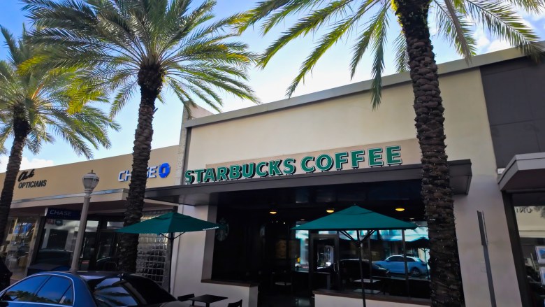Exterior view of a Starbucks Coffee store in Miami Beach, Florida, with palm trees and outdoor seating.