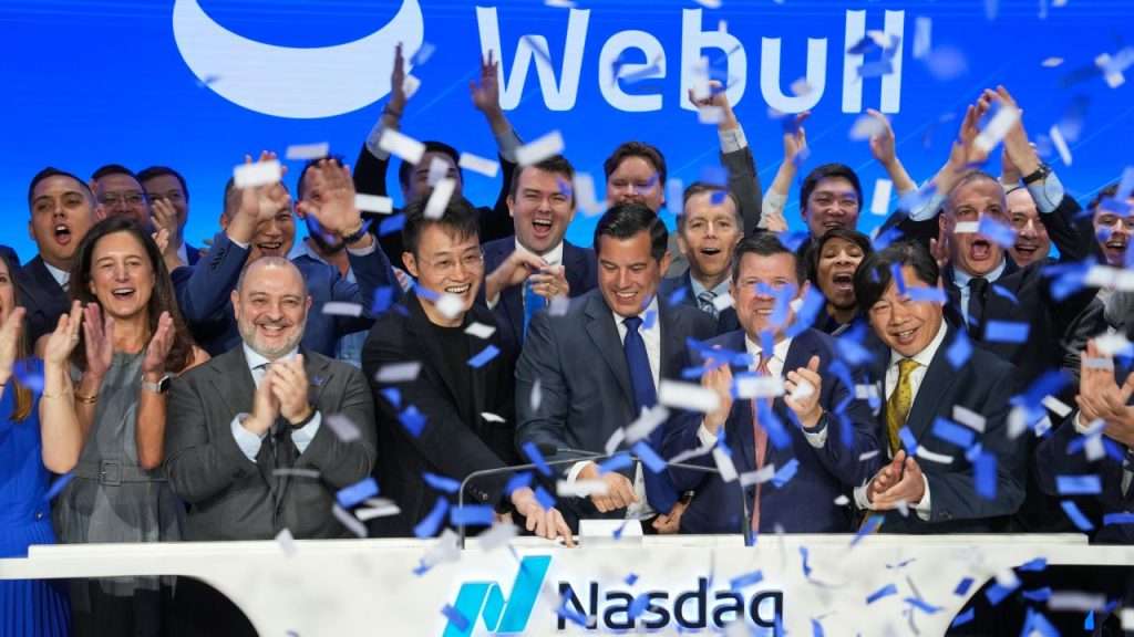 Webull executives and employees celebrate at the Nasdaq MarketSite as confetti falls.