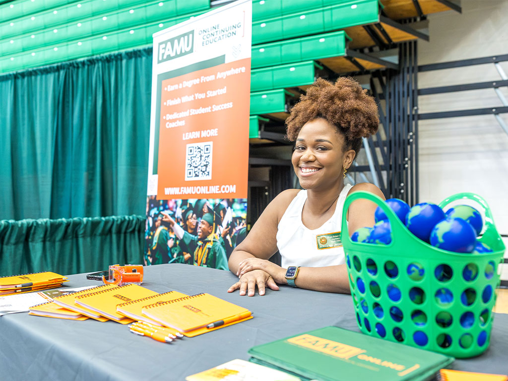 A Florida A&M University representative welcomes attendees at the FAMU Online Continuing Education booth during the Fall 2026 Career and Internship Expo on Sept. 30 at the Al Lawson Multipurpose Center. (Photo courtesy of Jeff Adams.)