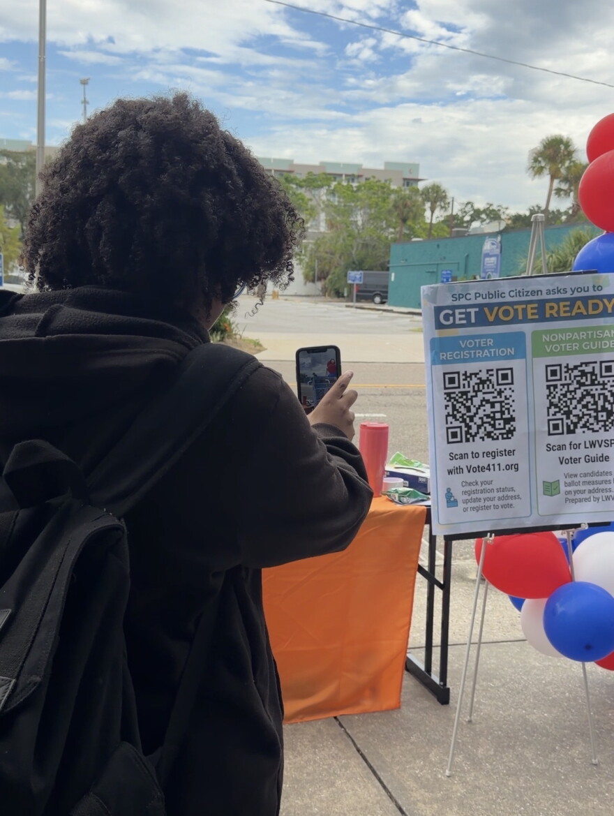SPC student uses QR code on poster board to check if they are registered.