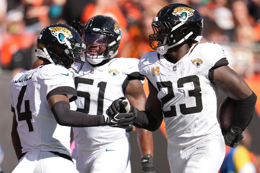 Jacksonville Jaguars players Foyesade Oluokun (23) and Jarrian Jones (4) celebrate with a teammate after an interception.