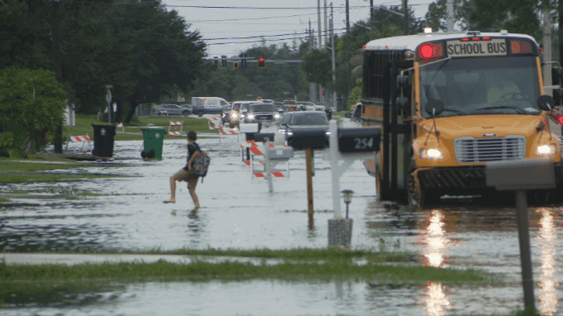 Students step off a school bus into floodwaters along Southwest Thornhill Drive in Port St. Lucie on Tuesday October 6, 20206, with one child carrying his shoes and walking barefoot through standing water after heavy rain flooded area roadways. (WPEC)