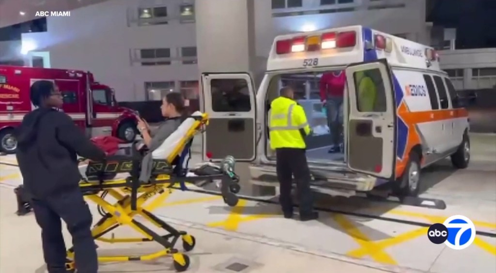 An ambulance at a hospital with medical personnel attending to a passenger on a stretcher.