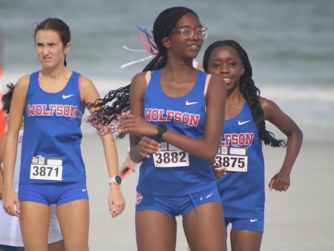 Wolfson's Lily Combs (3871), Kennedy Tatum (3882) and Kymra Harris (3875) warm up before the Nor'Eastern Classic high school cross country meet on Sept. 29, 2026 in Jacksonville Beach, Florida. [Clayton Freeman/Florida Times-Union]