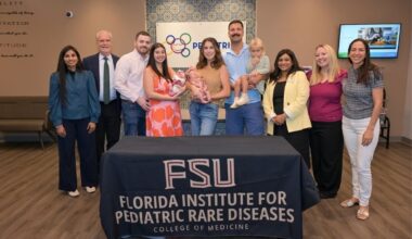 A group photo of several people in behind a tablecloth reading "FSU, Florida Institute for Pediatric Rare Diseases, College of Medicine"