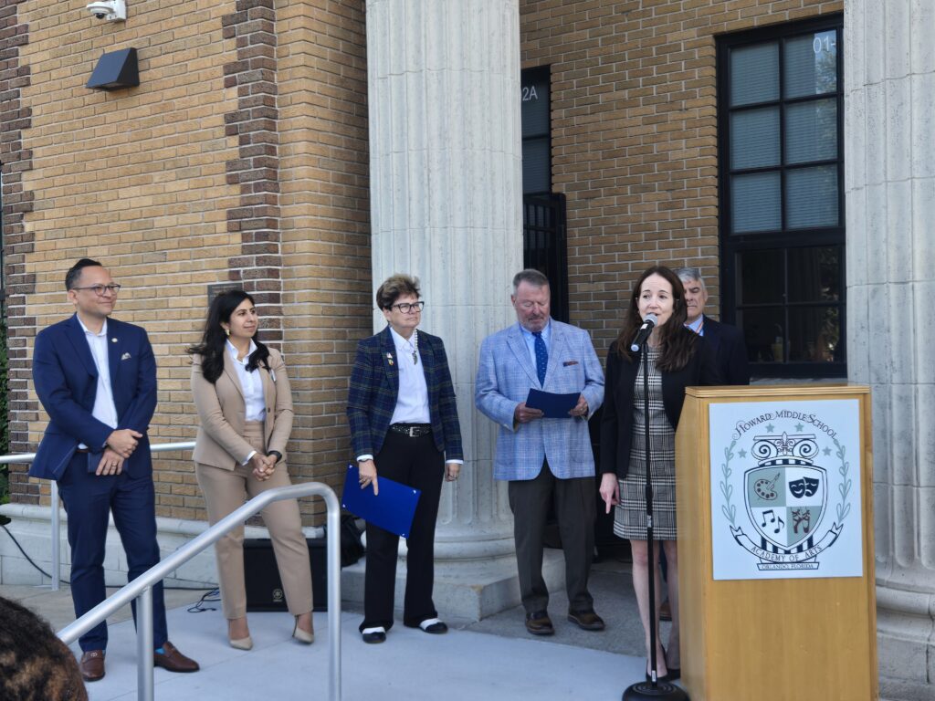 Dignitaries standing on the steps of an old school with pillars.