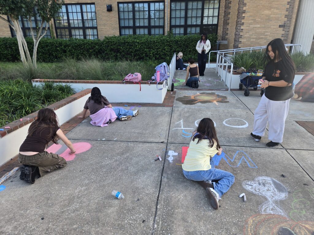 students creating chalk art on a sidewalk