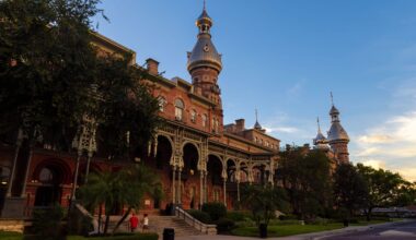 Historic Plant Hall at the University of Tampa, featuring red brick architecture, ornate verandas and distinctive silver minarets at sunset.