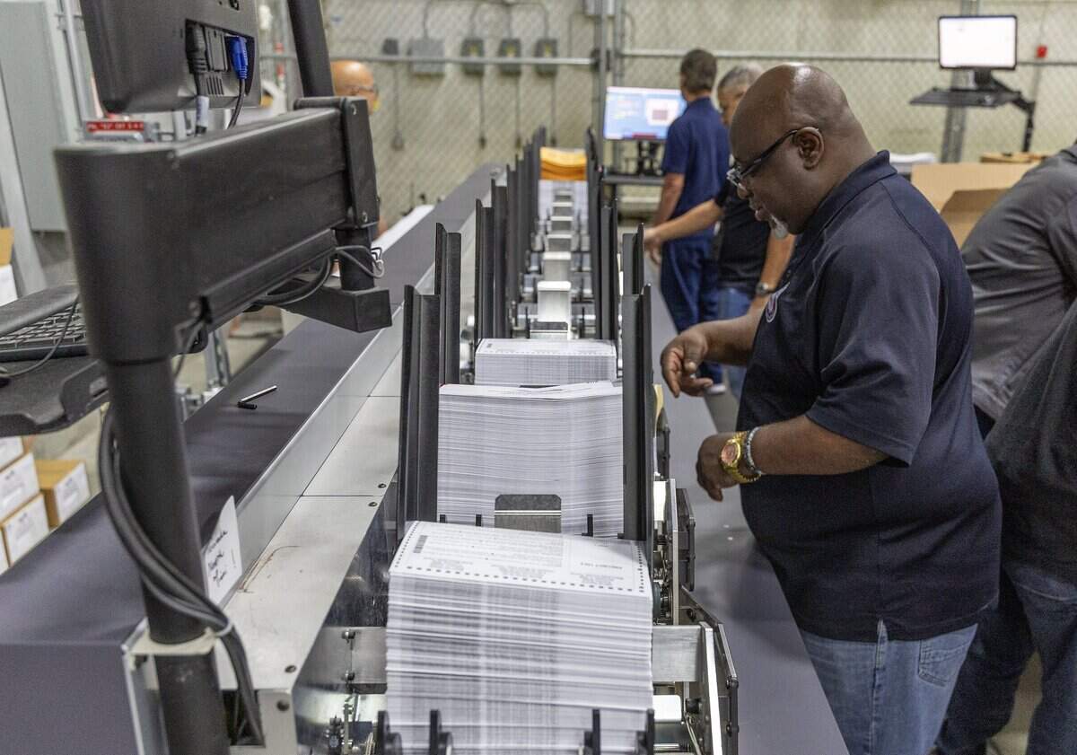 Willie McNickles, an election department employee, feeds ballots through an insertion machine as mail-in ballots are processed ahead of being sent out on Thursday, Sept. 24, by the Miami-Dade County Office of the Supervisor of Elections.
