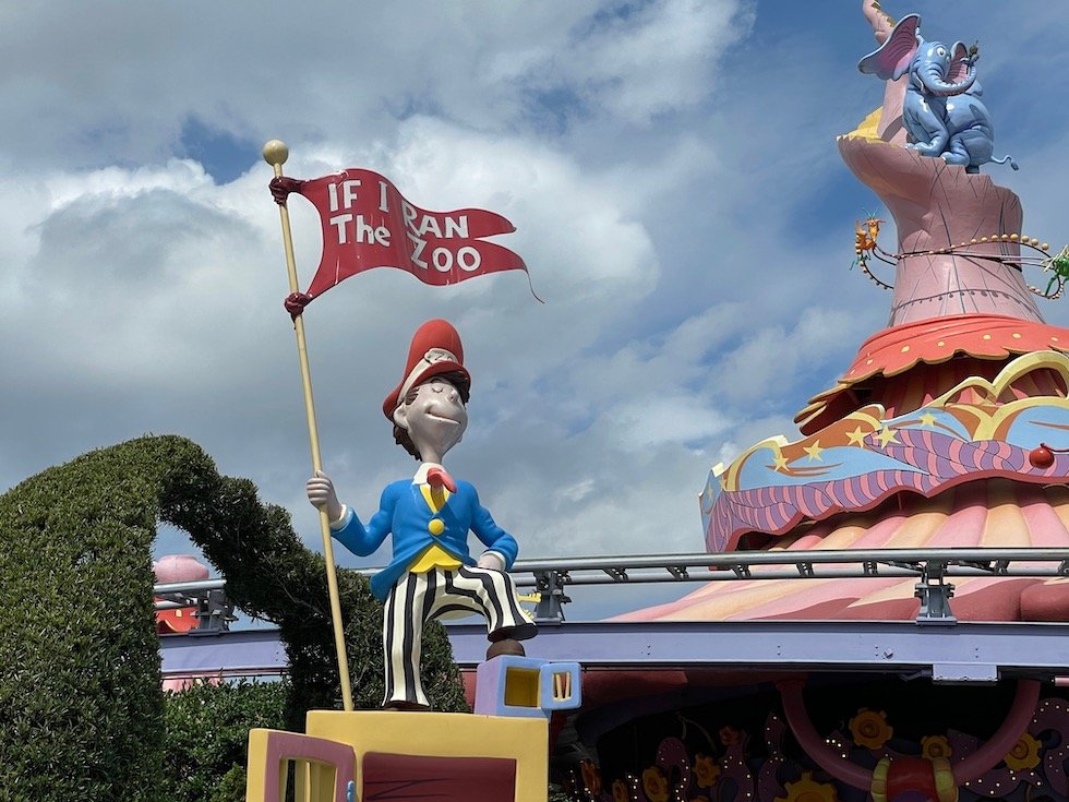 Dr. Seuss theme park decor at Universal Islands of Adventure, including a character holding a flag reading If I Ran The Zoo."