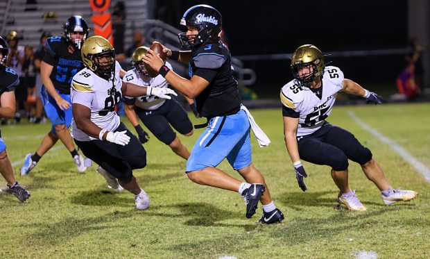 Bishop Moore defenders Deion Plummer (99) and Mateo Rivera (55) circle in on Hagerty quarterback Royce Jenkins (3) during Bishop Moore's 42-0 victory on Friday night. Bishop Moore had 5 sacks in the game. (Chris Hays/Orlando Sentinel)