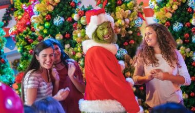 The Grinch with a mischievous smile in front of holiday decor