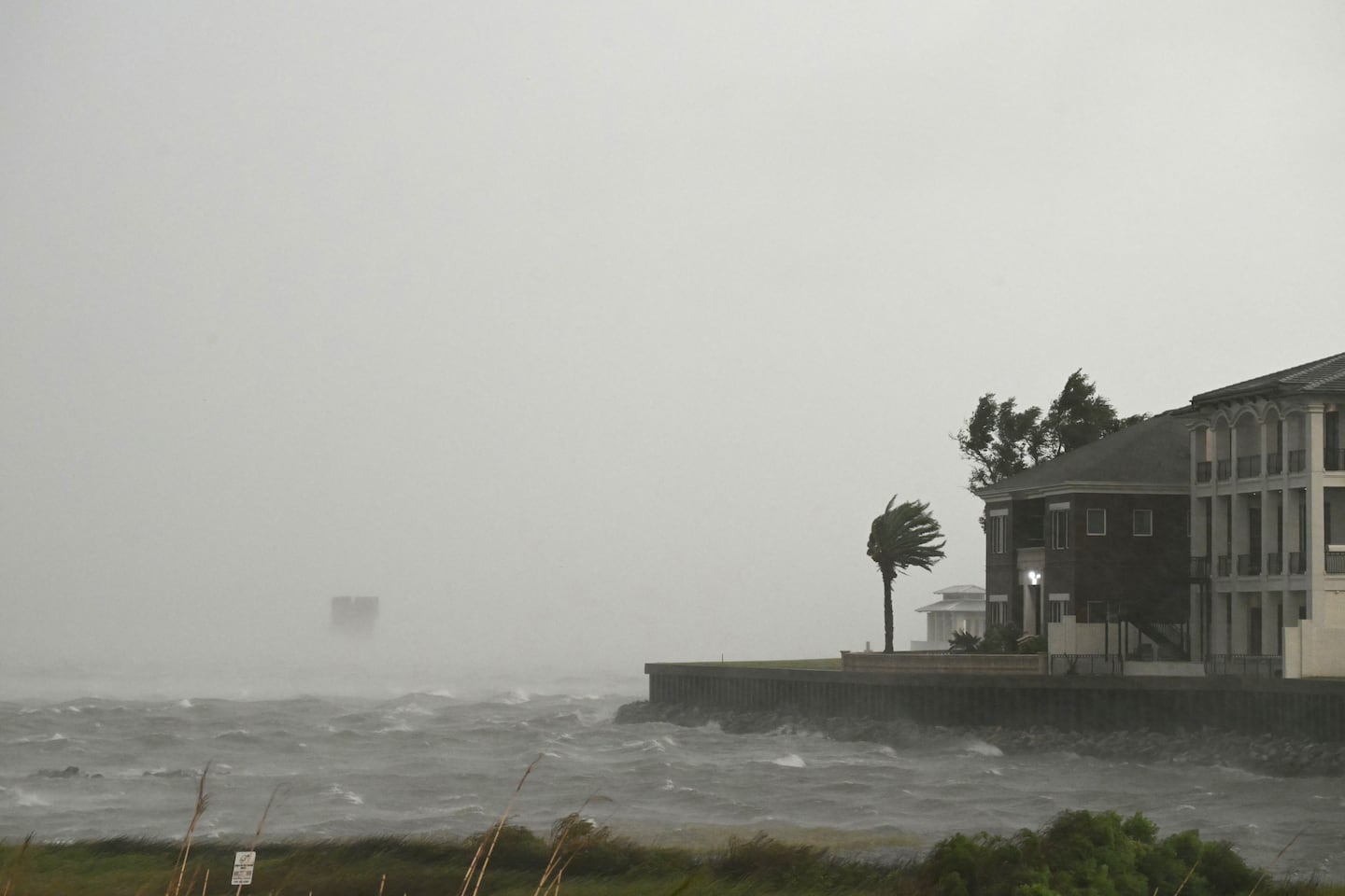 A house is battered by the strong winds and storm surge of Hurricane Isaias in Pensacola, Florida, on Oct. 9, 2026. Hurricane Isaias' outer bands were lashing the US Gulf Coast with heavy rain and strong winds Friday, with the category 3 storm triggering mandatory evacuations and poised to bring life-threatening storm surge when it makes landfall.